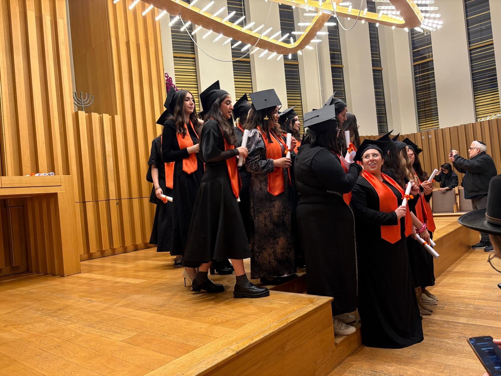 Diplômées en toge et écharpe orange recevant leur diplôme à l'IAD Business School