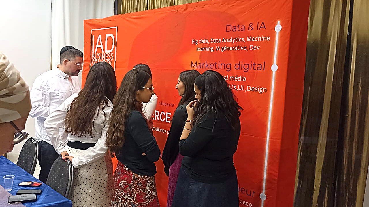 Gabriel Soussan échangeant avec les étudiants de l'IAD Business School devant le stand IAD Business School après la conférence sur l'IA et les RH